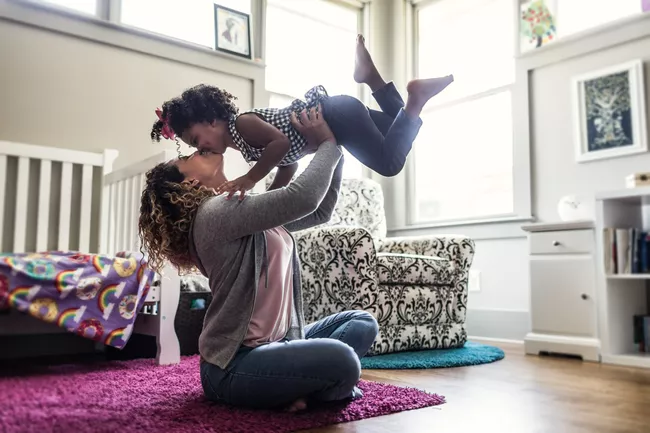 Mother and daughter playing on bedroom floor